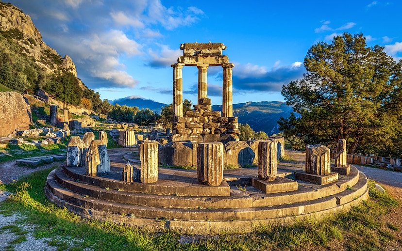 Ruins of the Temple of Athena Pronaia in Delphi, Greece, with surrounding landscape.
