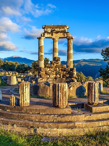 Ruins of the Temple of Athena Pronaia in Delphi, Greece, with surrounding landscape.