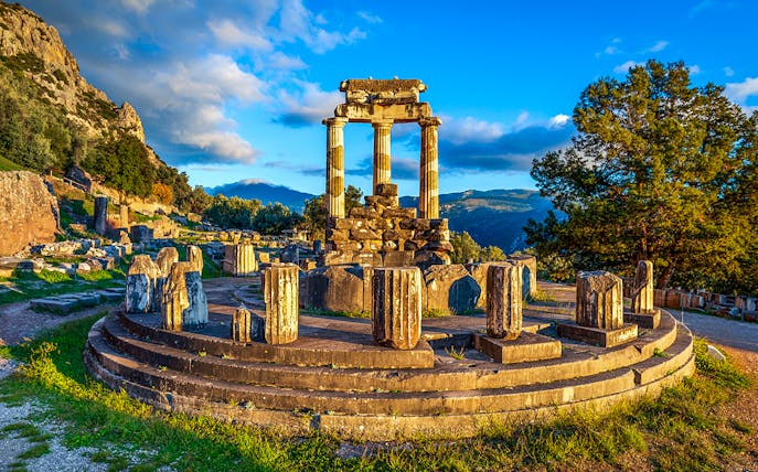 Ruins of the Temple of Athena Pronaia in Delphi, Greece, with surrounding landscape.