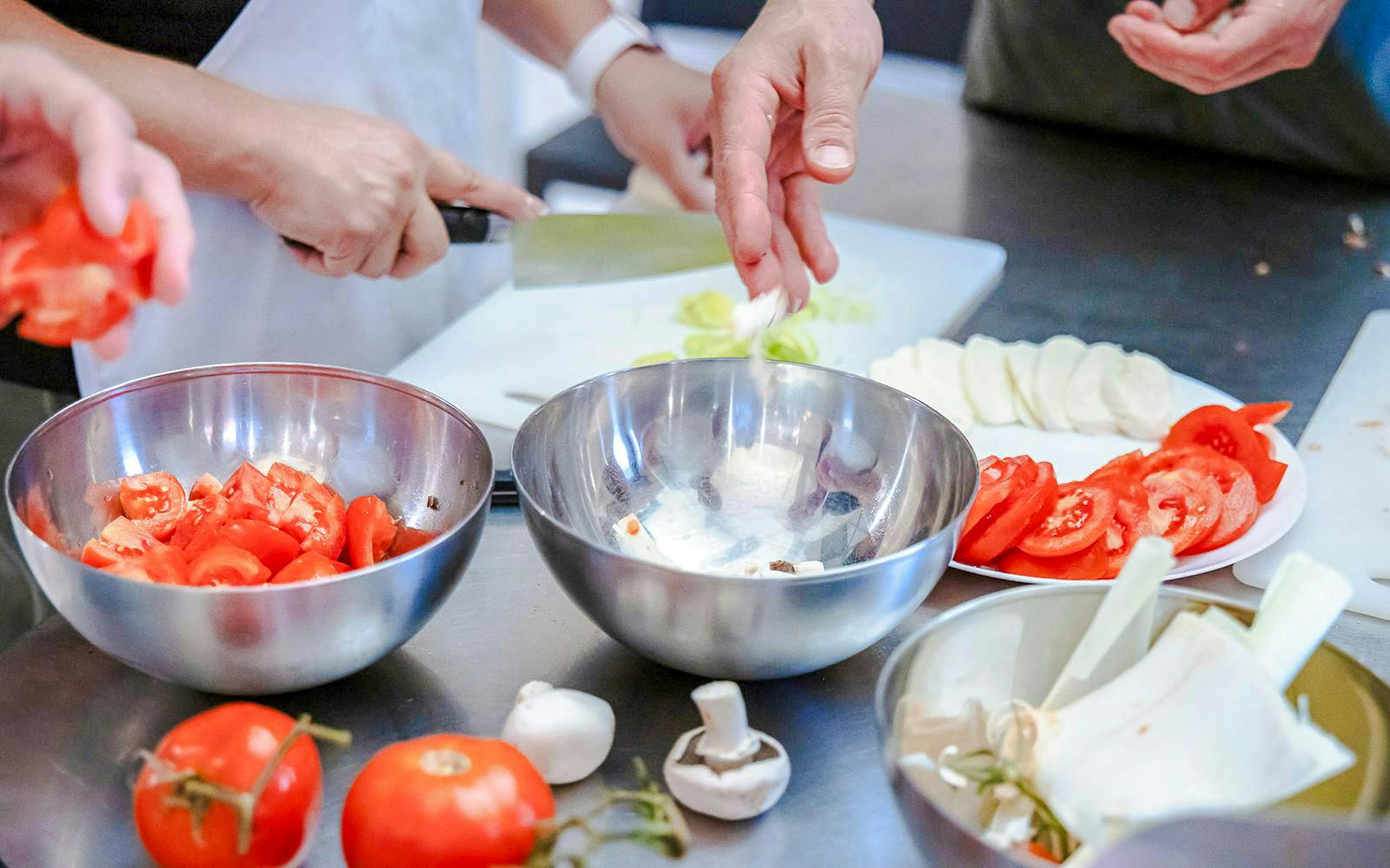 Hands preparing ingredients in a small group cooking class in Florence.