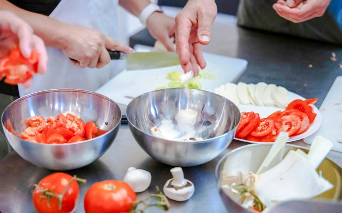 Hands preparing ingredients in a small group cooking class in Florence.