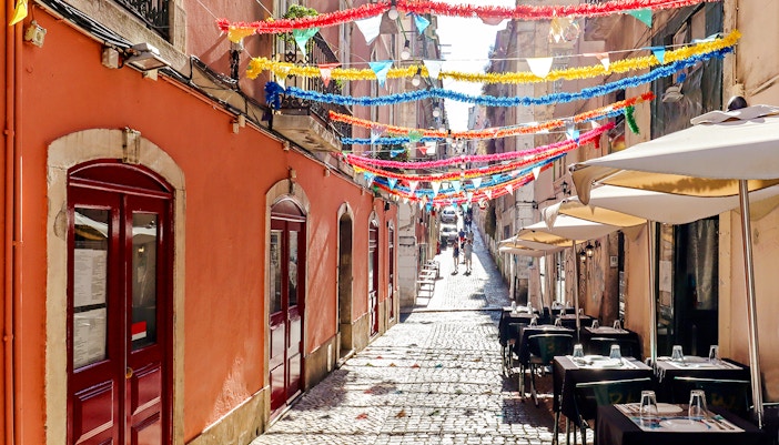 Bairro Alto street with colorful decorations and outdoor cafes in Lisbon.