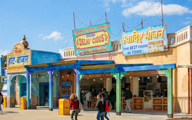 Delhicious restaurant entrance at Walibi Park with colorful signs and visitors.