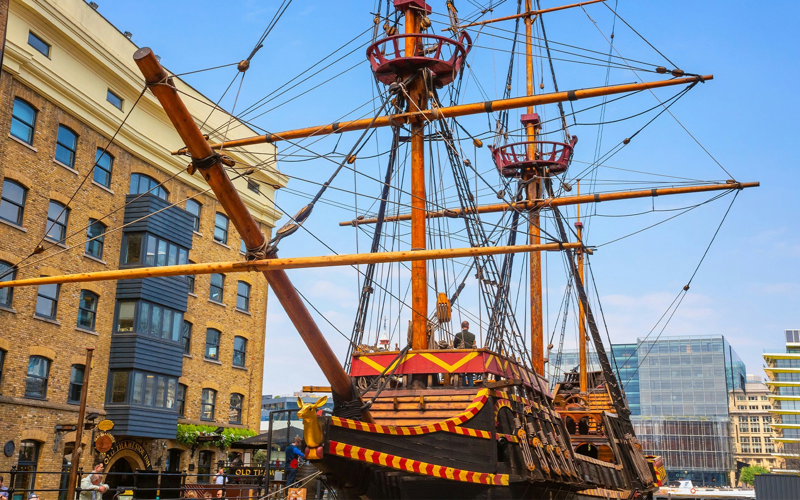 Historic ship replica docked near brick building in London.