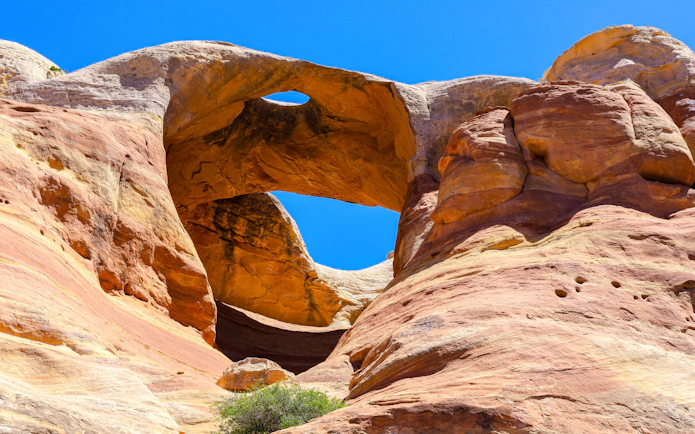Bridge Arch rock formation in Rattlesnake Canyon under clear blue sky.