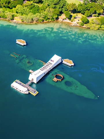 USS Arizona Memorial at Pearl Harbor, Hawaii, with tour boats and visitors.