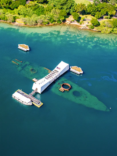USS Arizona Memorial at Pearl Harbor, Hawaii, with tour boats and visitors.