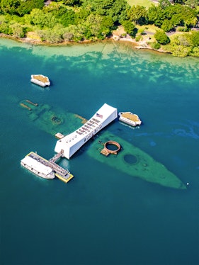 USS Arizona Memorial at Pearl Harbor, Hawaii, with tour boats and visitors.