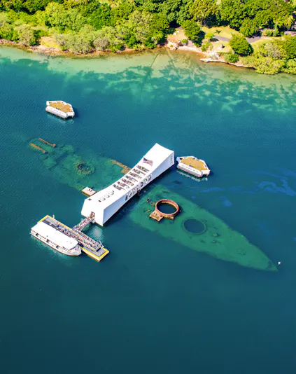 USS Arizona Memorial at Pearl Harbor, Hawaii, with tour boats and visitors.