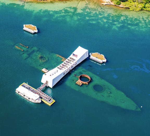 USS Arizona Memorial at Pearl Harbor, Hawaii, with tour boats and visitors.