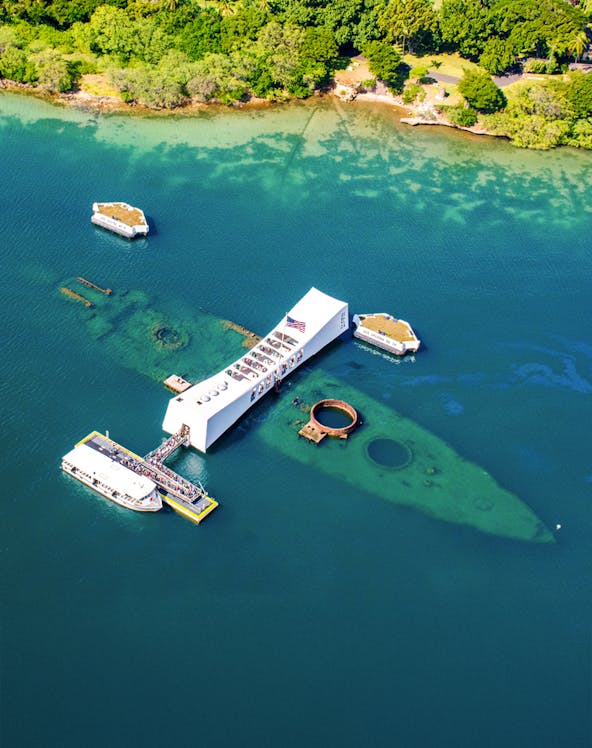 USS Arizona Memorial at Pearl Harbor, Hawaii, with tour boats and visitors.