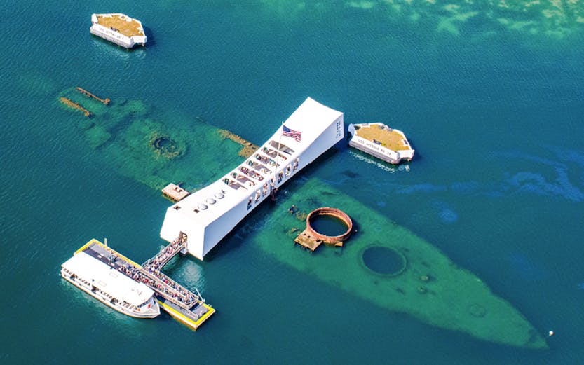 USS Arizona Memorial at Pearl Harbor, Hawaii, with tour boats and visitors.