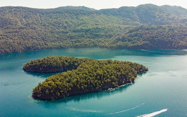 Aerial view of Isla Corazón on Lake Mascardi, surrounded by lush forest and clear water.