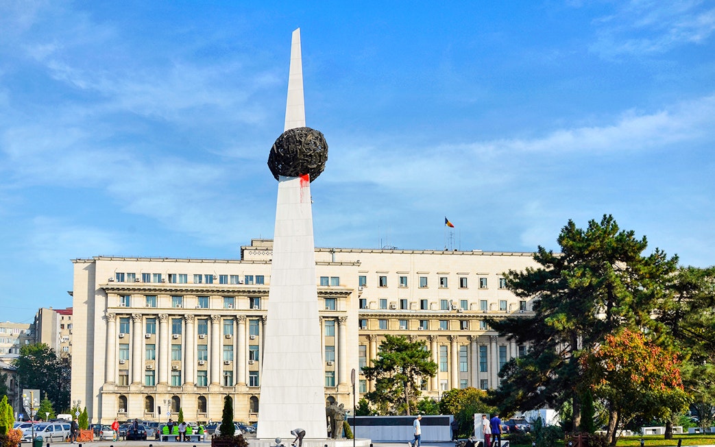 Memorial of Rebirth monument in Revolution Square, Bucharest, with surrounding buildings.