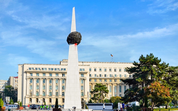 Memorial of Rebirth monument in Revolution Square, Bucharest, with surrounding buildings.