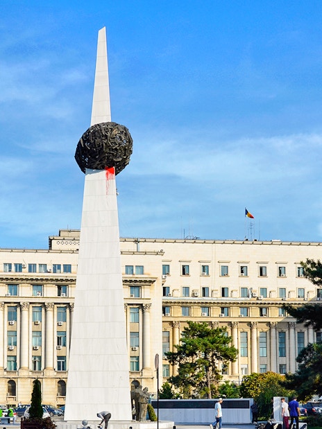 Memorial of Rebirth monument in Revolution Square, Bucharest, with surrounding buildings.