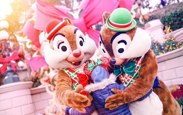Chipmunks hugging a child at Disneyland Christmas 2025 celebration.
