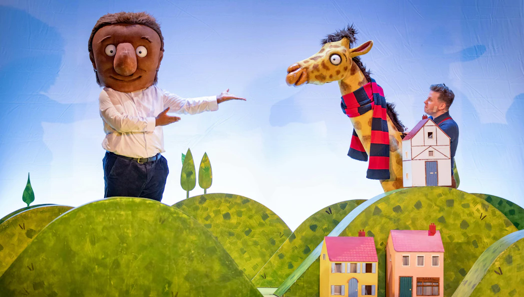 Giant character and giraffe puppet on stage in "The Smartest Giant in Town" show.
