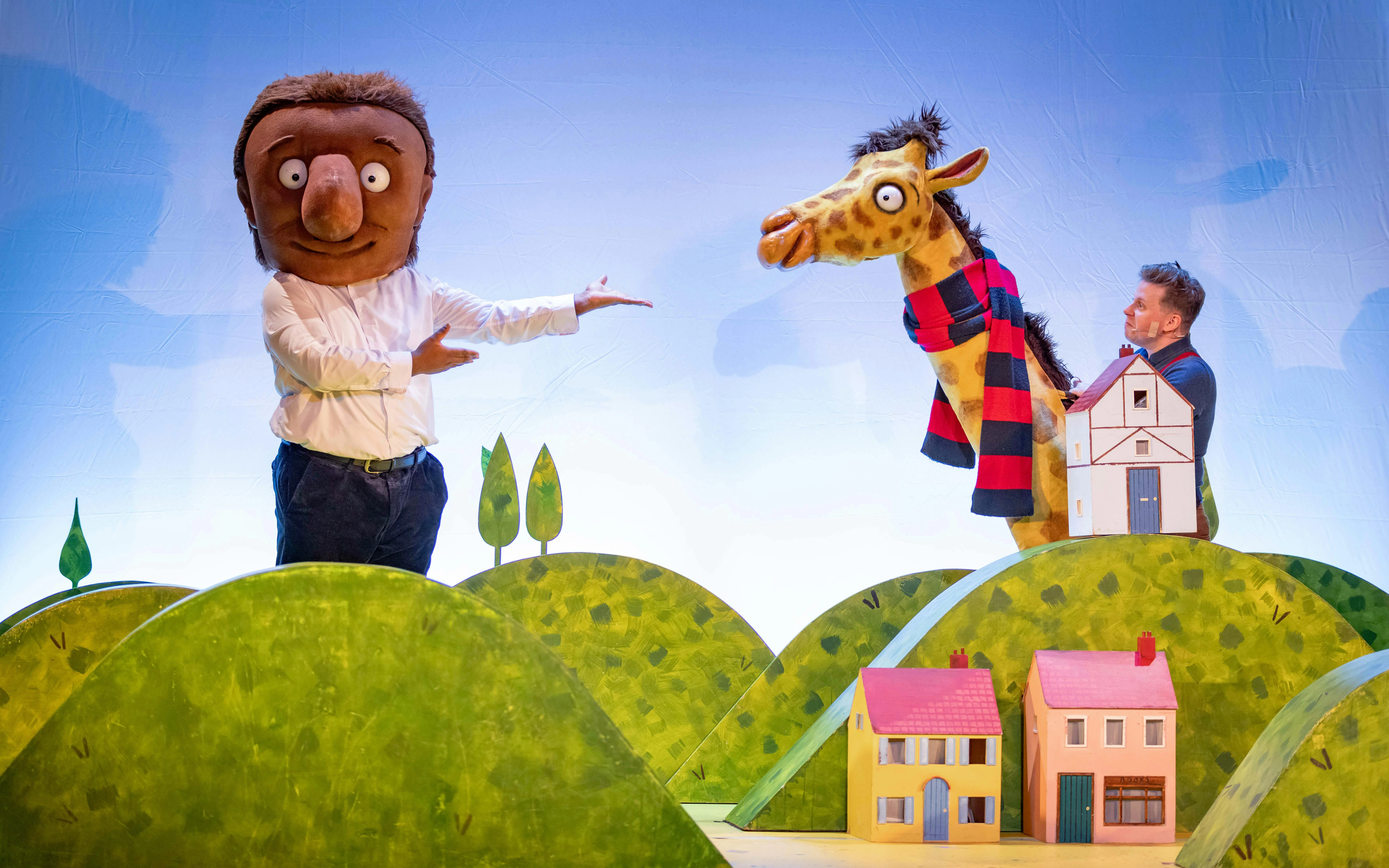 Giant character and giraffe puppet on stage in "The Smartest Giant in Town" show.