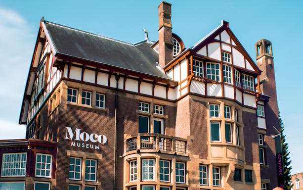 Moco Museum Amsterdam exterior with brick facade and large windows.