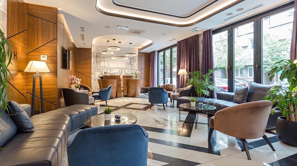 Modern luxury hotel reception with stylish seating and decorative plants.