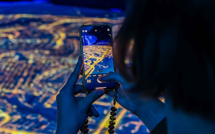 Visitor capturing digital map at Amsterdam in Motion exhibit.