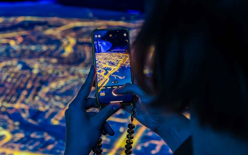 Visitor capturing digital map at Amsterdam in Motion exhibit.