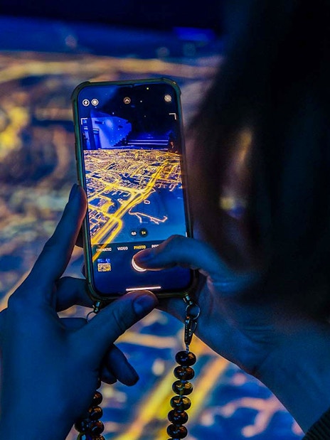 Visitor capturing digital map at Amsterdam in Motion exhibit.