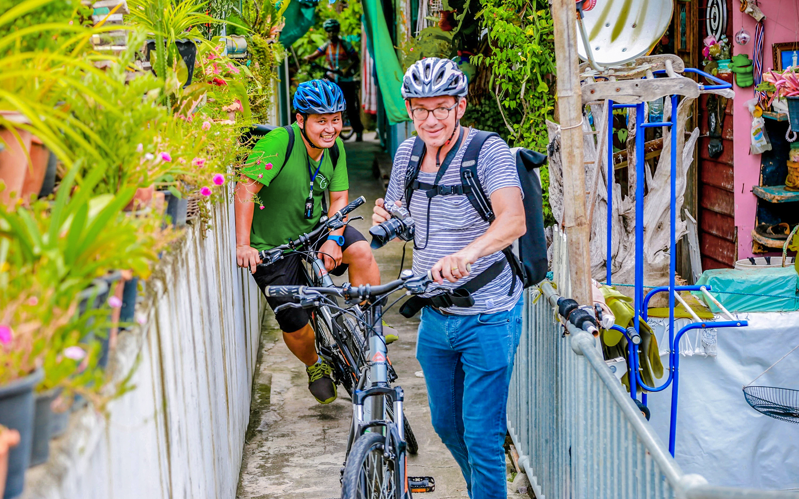 Cyclists navigating narrow backstreets on a guided tour in Bangkok.