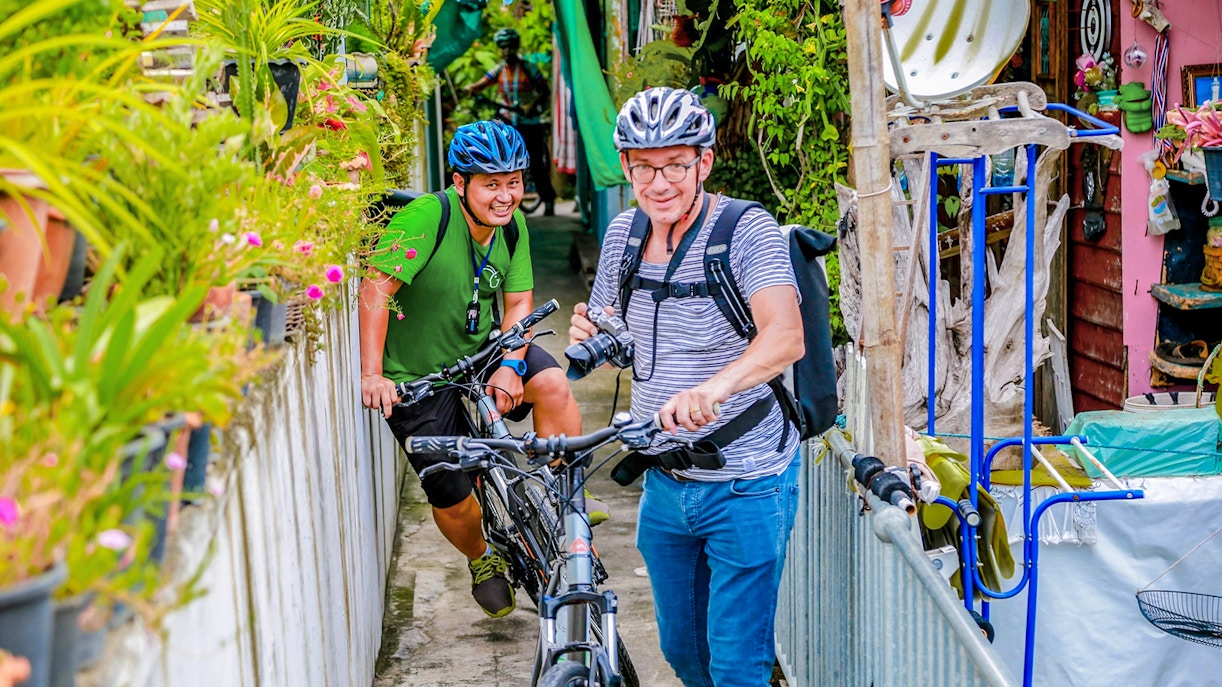 Cyclists navigating narrow backstreets on a guided tour in Bangkok.