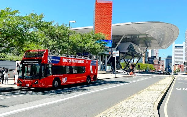 Red Boston sightseeing bus near a modern building in the city center.