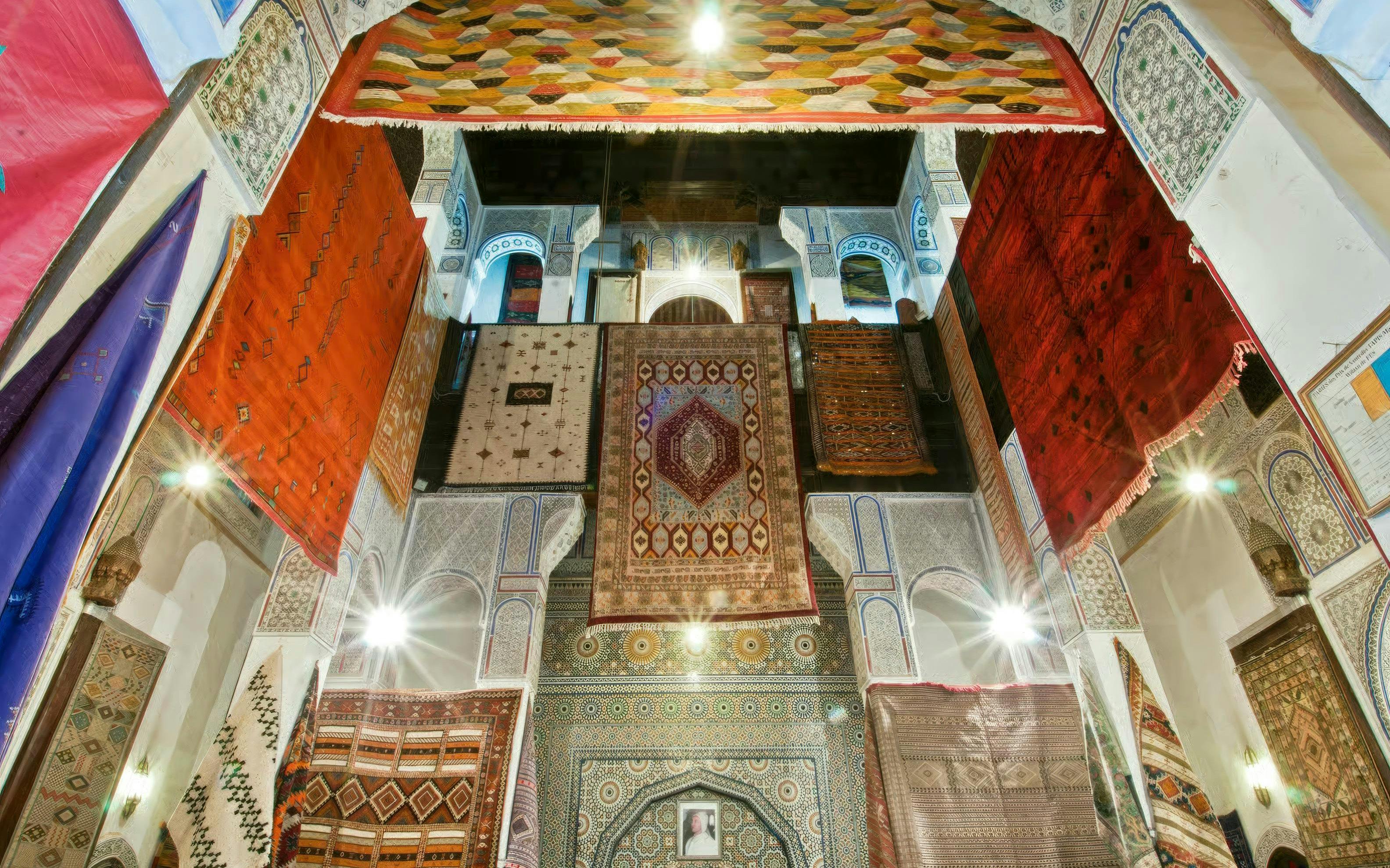 Colorful carpets hanging in a traditional Moroccan building in Fes Medina.