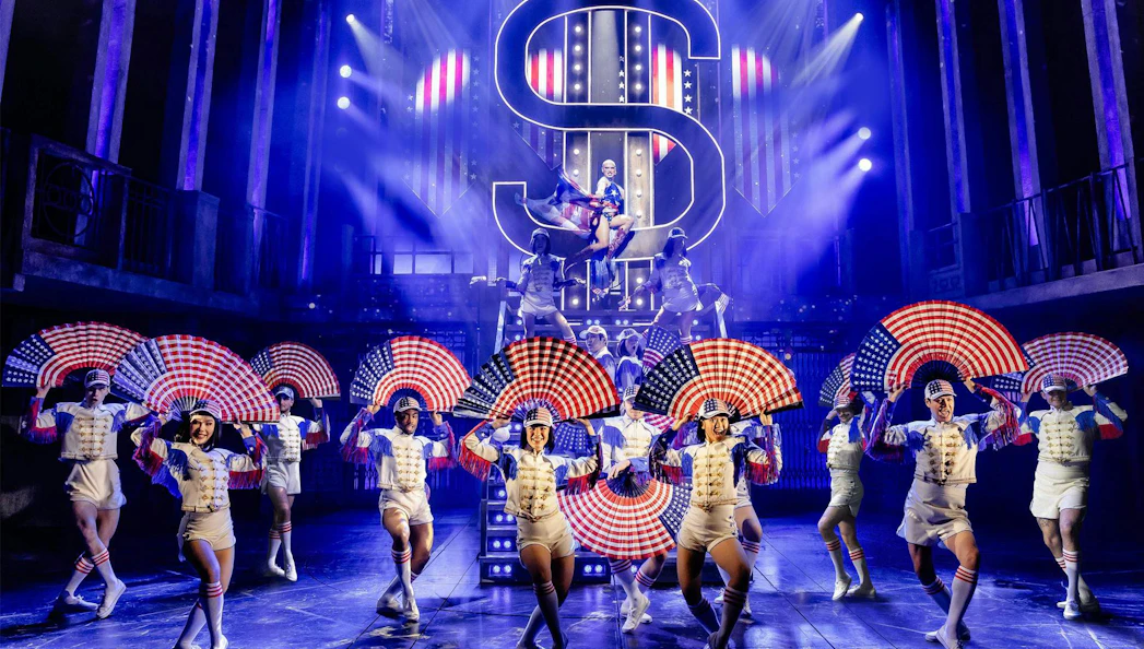 Performers with American flag fans on stage in Miss Saigon, West End.
