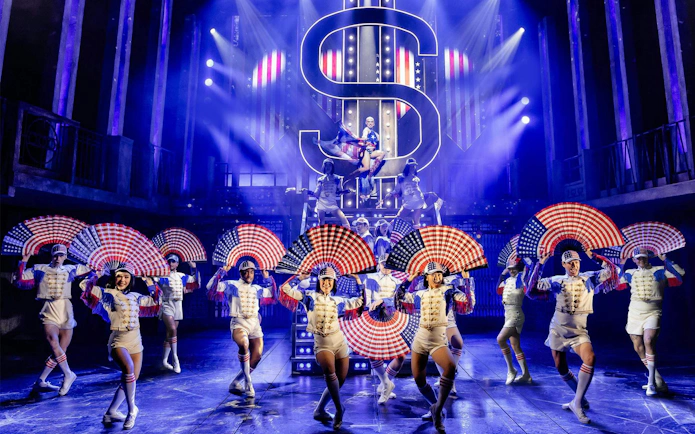 Performers with American flag fans on stage in Miss Saigon, West End.