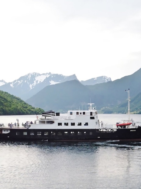 Sightseeing cruise ship on Hjørundfjord, surrounded by mountains, Norway.