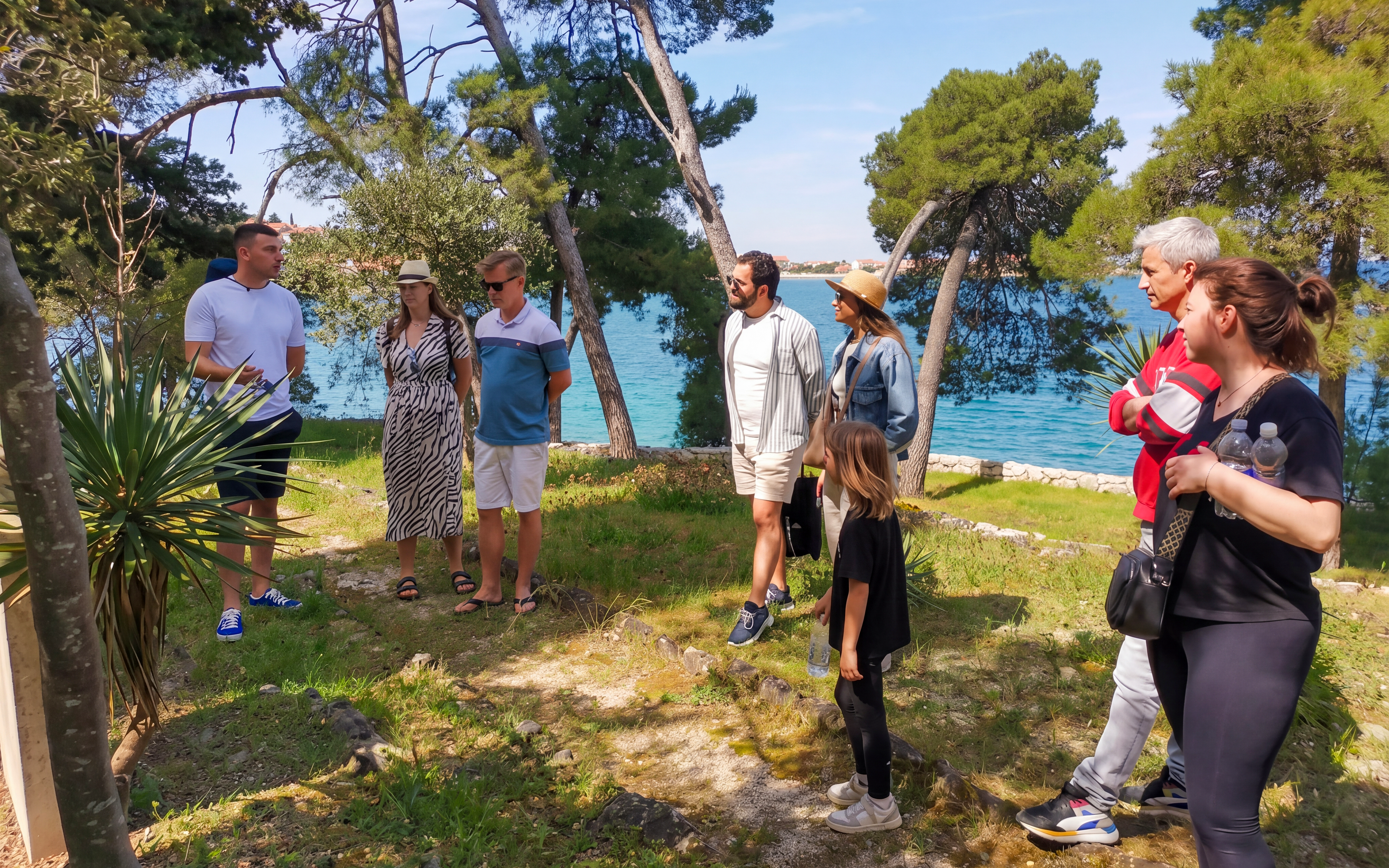 Group listening to a guide near the sea in Zadar during a speedboat tour.