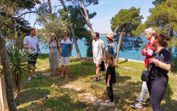 Group listening to a guide near the sea in Zadar during a speedboat tour.