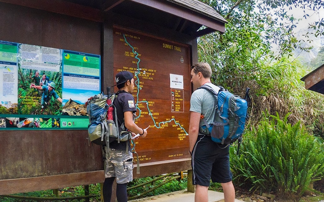 Hikers examining trail map at Mount Kinabalu Summit Tour starting point.