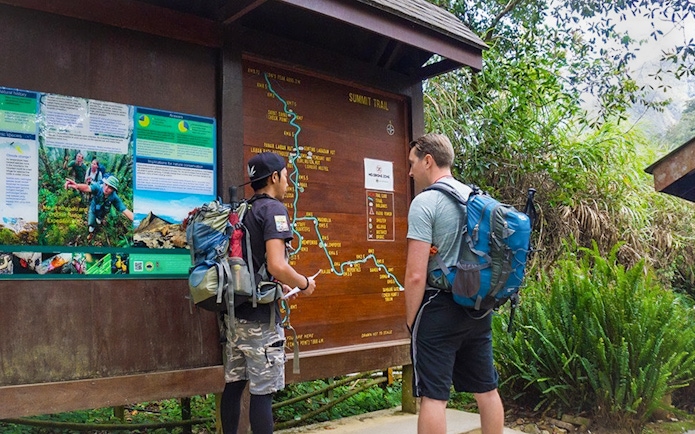Hikers examining trail map at Mount Kinabalu Summit Tour starting point.