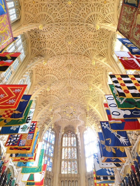 Westminster Abbey interior with colorful banners and ornate ceiling, Royal London Tour.