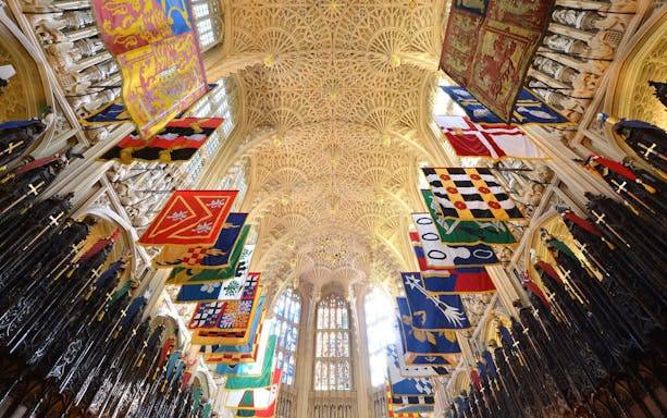 Westminster Abbey interior with colorful banners and ornate ceiling, Royal London Tour.