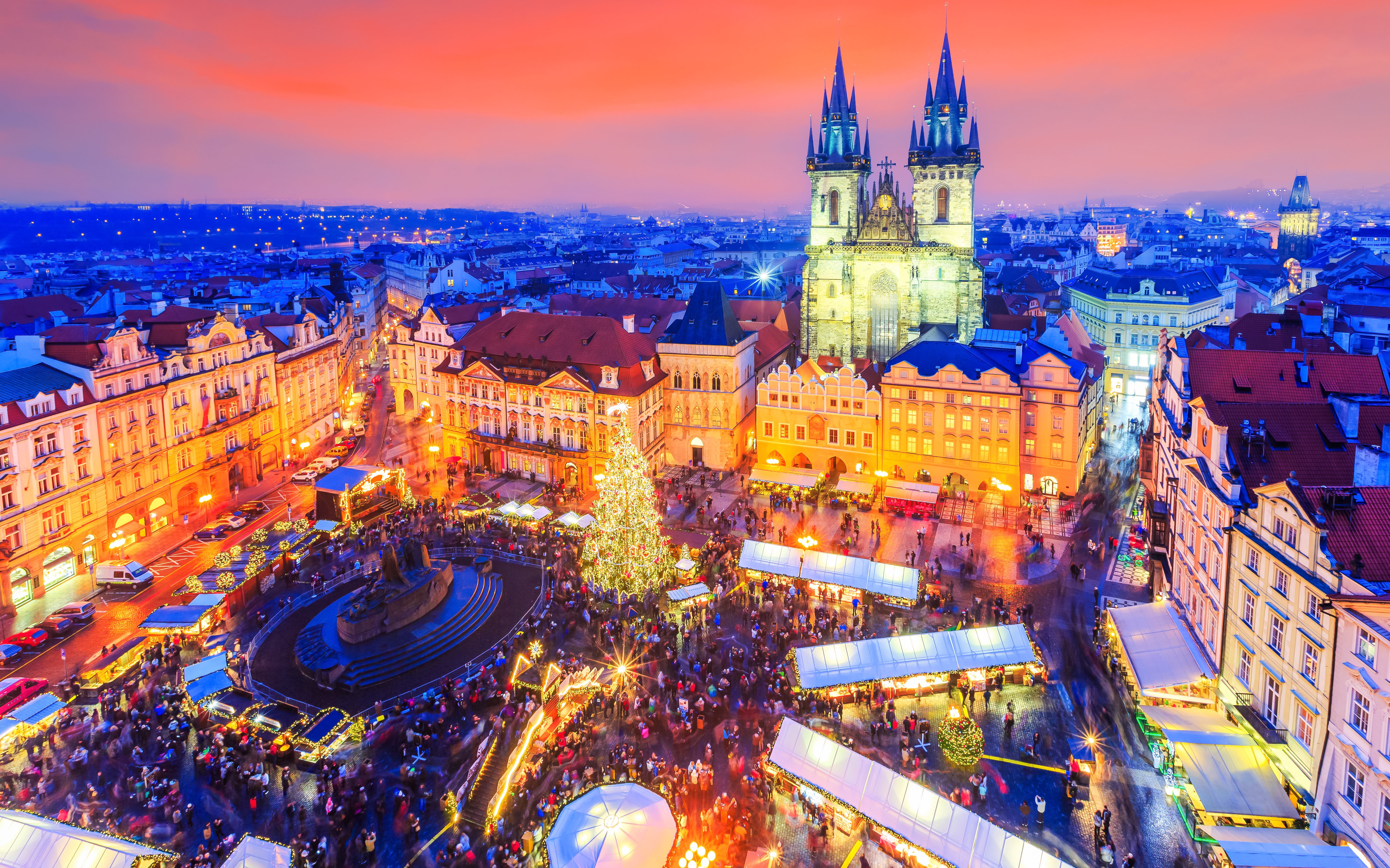 Old Town Square with Christmas market and lights in Prague, featuring Tyn Church at sunset.