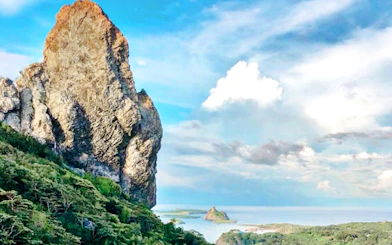 Rocky peak and lush greenery on Noronha Piquinho Trail with ocean view, Sao Paulo.