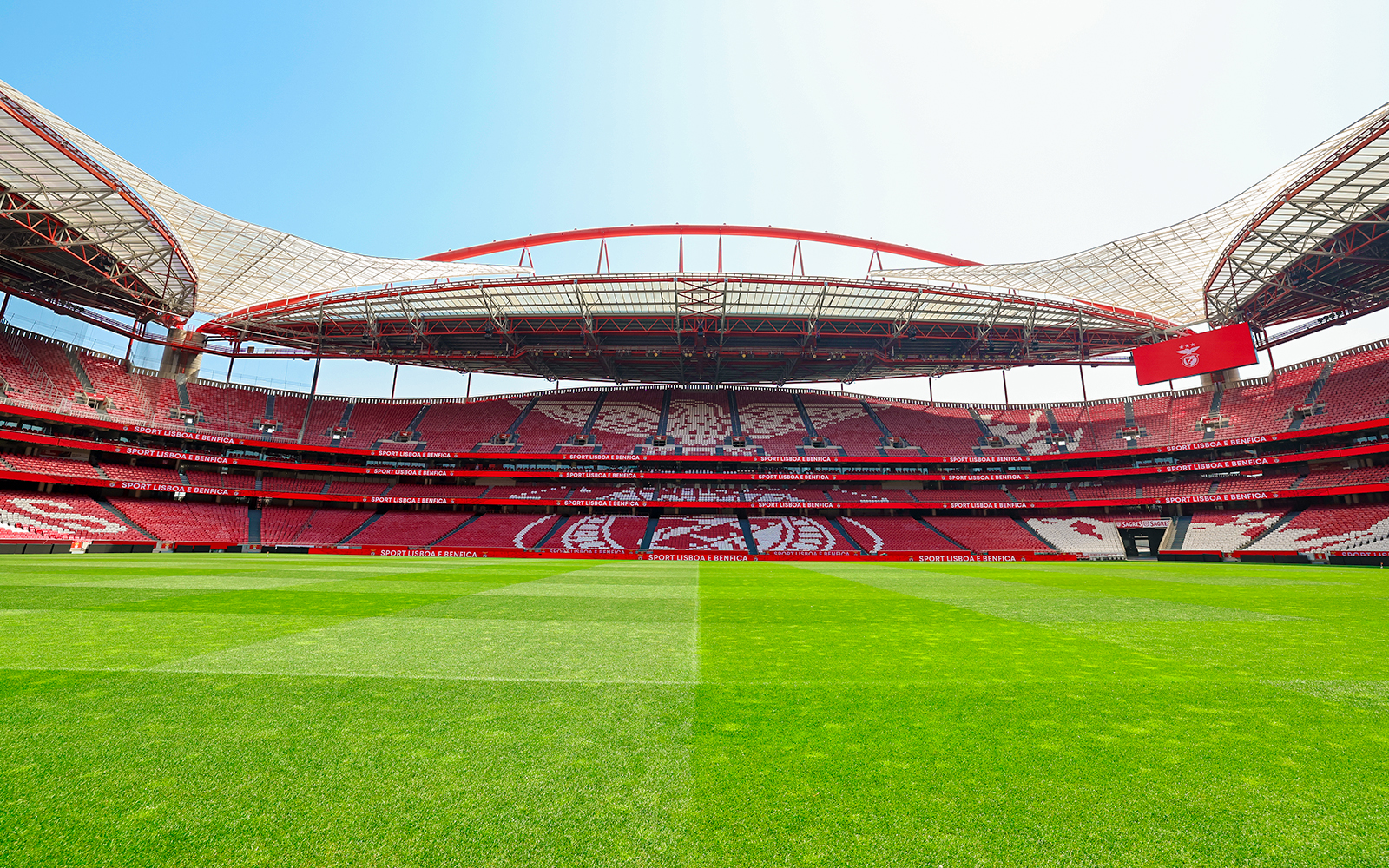 Benfica Stadium ground with lush green field and iconic red seating in Lisbon, Portugal.