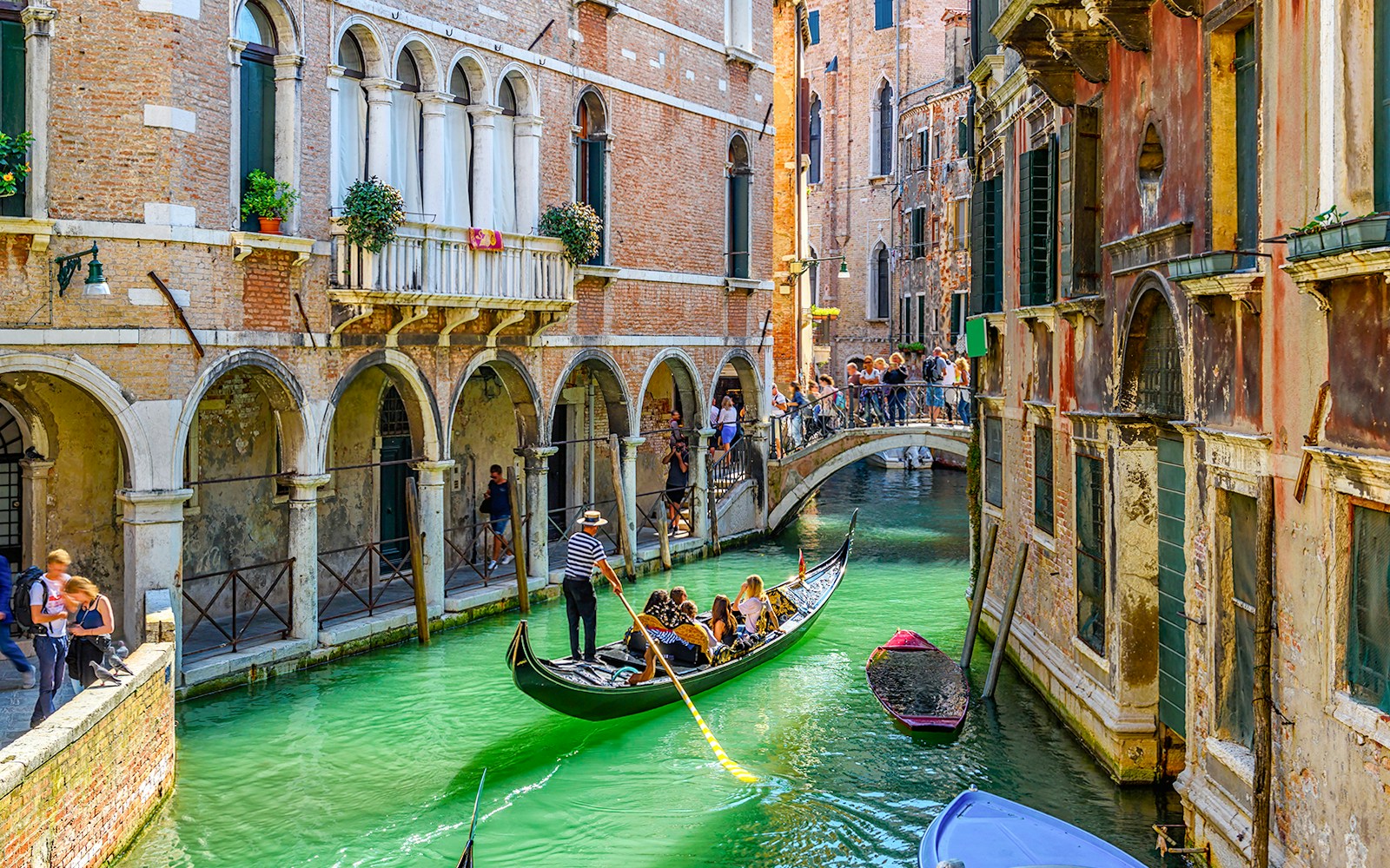 Gondola gliding under a stone bridge on a narrow canal in Venice, Italy.