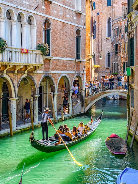 Gondola navigating a narrow canal under a bridge in Venice, Italy.