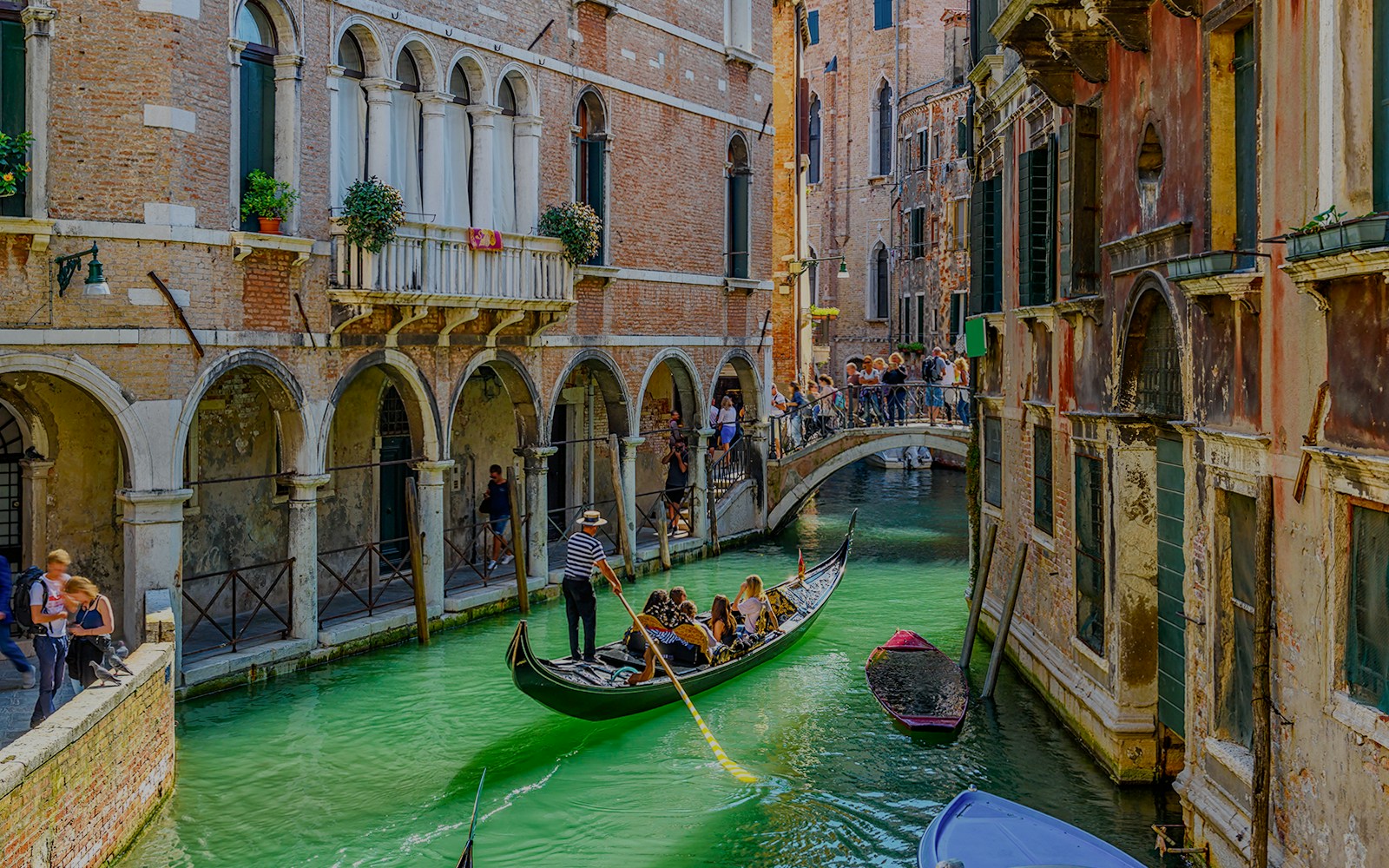 Gondola gliding under a stone bridge on a narrow canal in Venice, Italy.