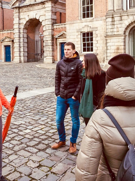 Tour guide with group in a historic courtyard, discussing local architecture.