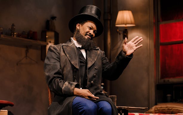 Performer in a top hat gesturing during a scene from "Topdog/Underdog" play.