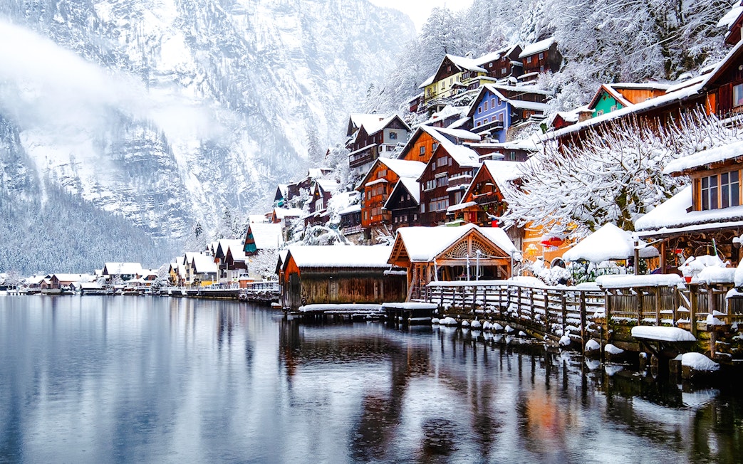 Hallstatt village in Austria covered in snow during winter, with colorful houses by the lake.
